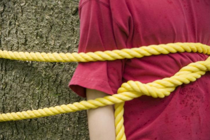 jongen vastgebonden aan een boom